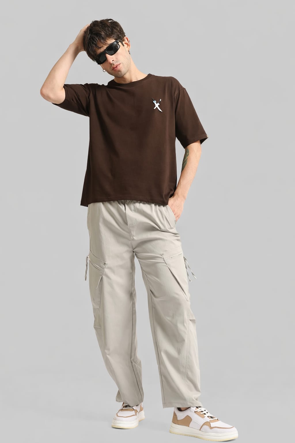 Person wearing a brown t-shirt and beige cargo pants on a gray background