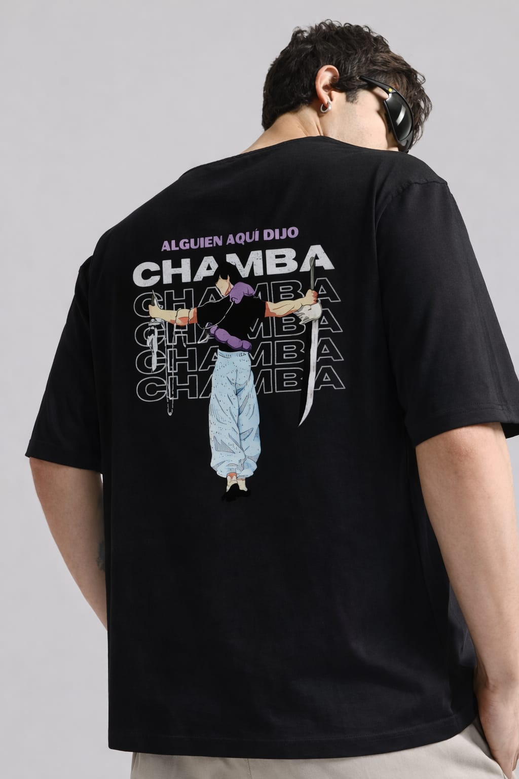 Person wearing a black t-shirt with graphic design and text on the back against a gray background